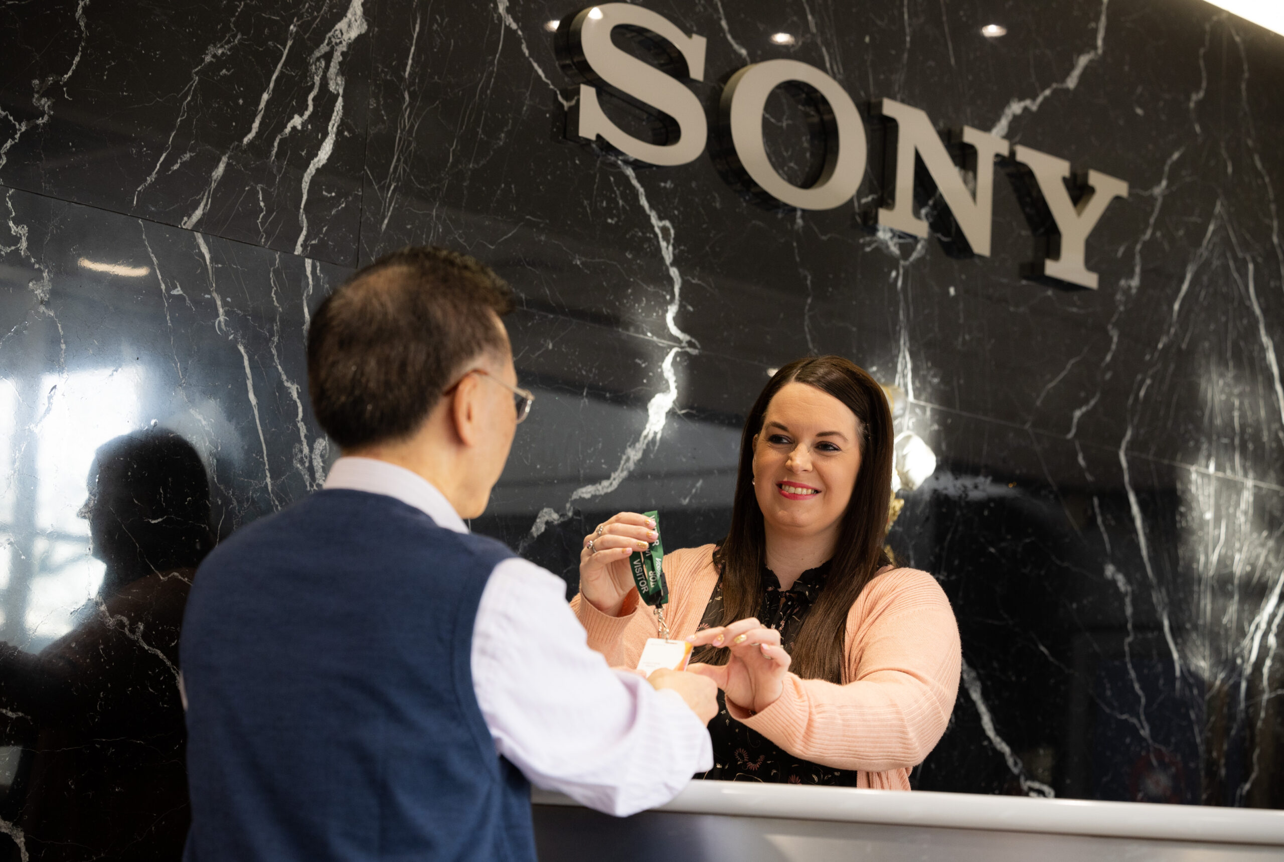 A photo of a visitor being greeted by a receptionist