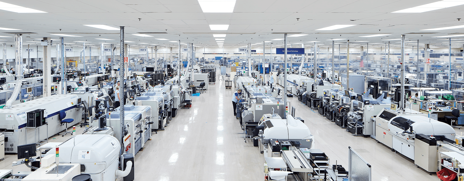 An areal photo of a factory floor with rows of white machines.
