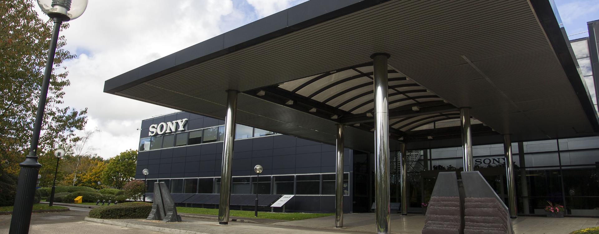 A photo of the Sony UK Technology Centre building. The outside of the building is black, and a white Sony logo is positioned at the top left corner of the building.